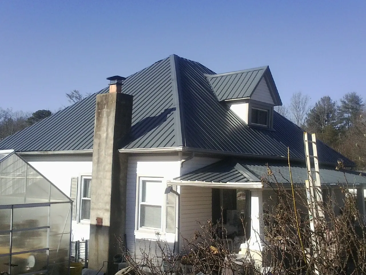 Dark blue standing seam metal roof on a white farmhouse with dormer — Slate & Tile Roof Repair by Roofing Brothers in Novato