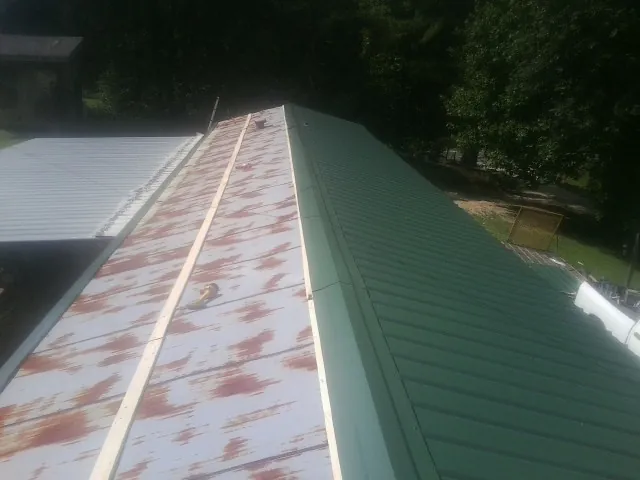 Old rusted panels beside newly installed green metal roofing — Wind Damage Roof Repair by Roofing Brothers in Novato