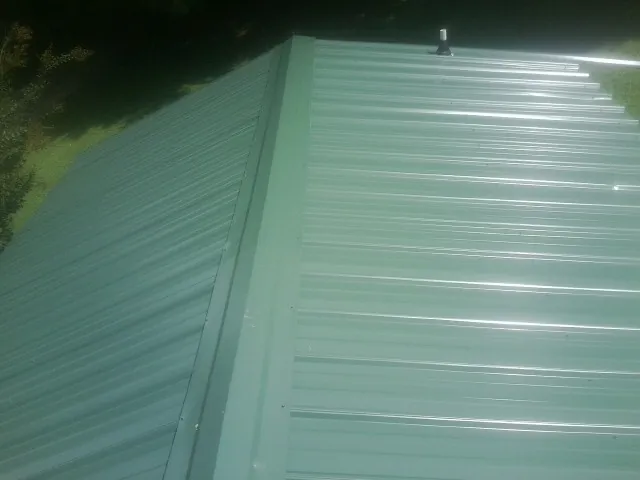 New green metal panels meeting at the ridge of a roof — Flat Roof Repair work by our crew in Novato