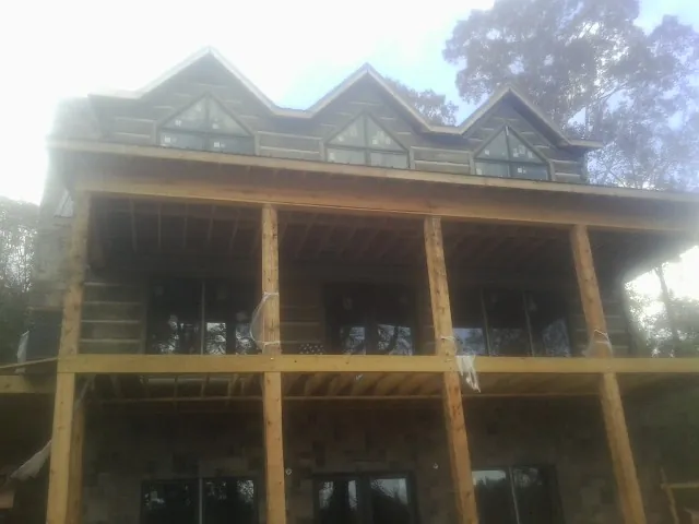 Dormers and porch framing on a large log home under construction — Roof Coating work by our crew in Novato