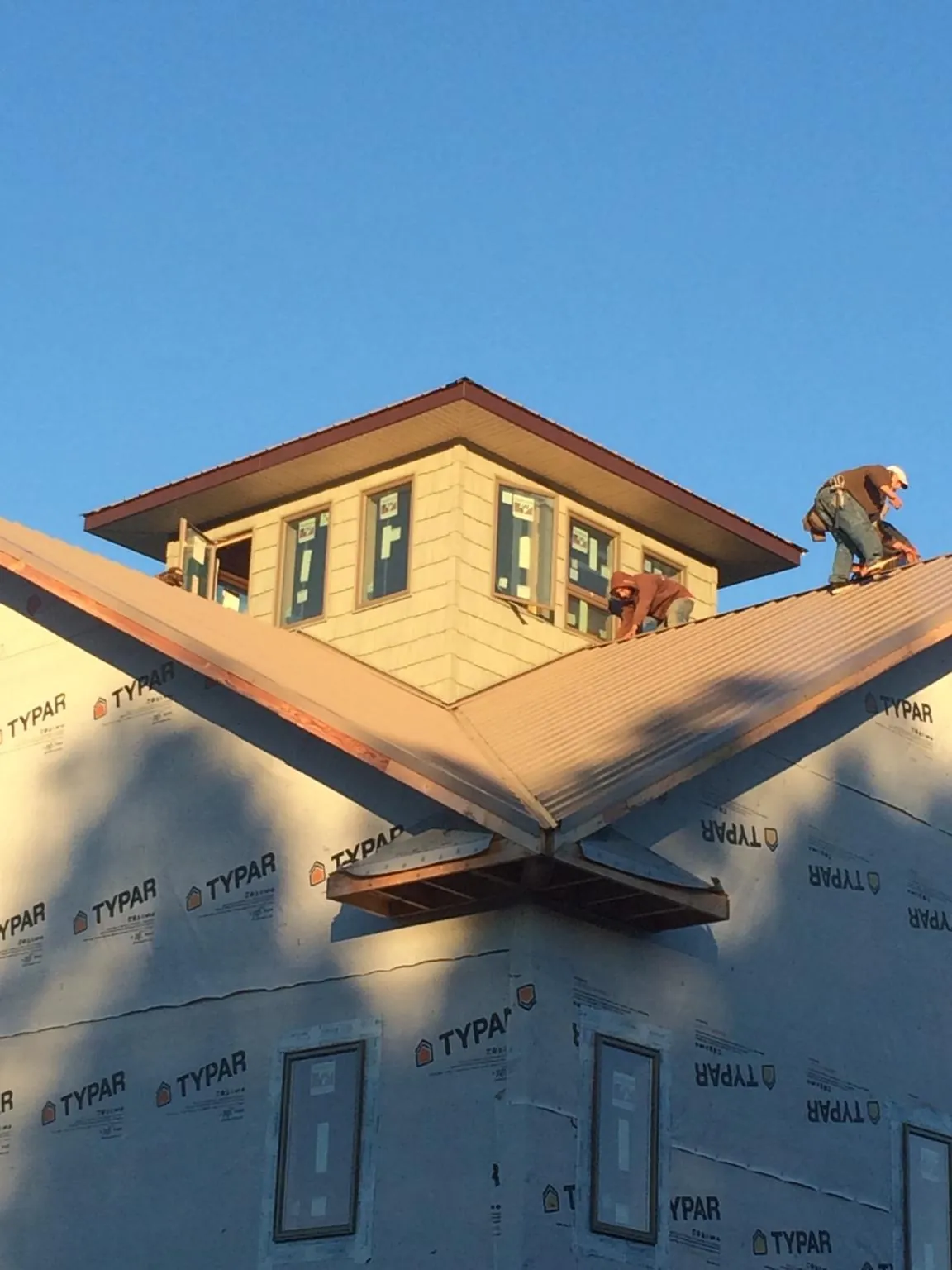 Roofers working around a rooftop cupola on a new metal roof at sunset — Roof Waterproofing in Novato by Roofing Brothers